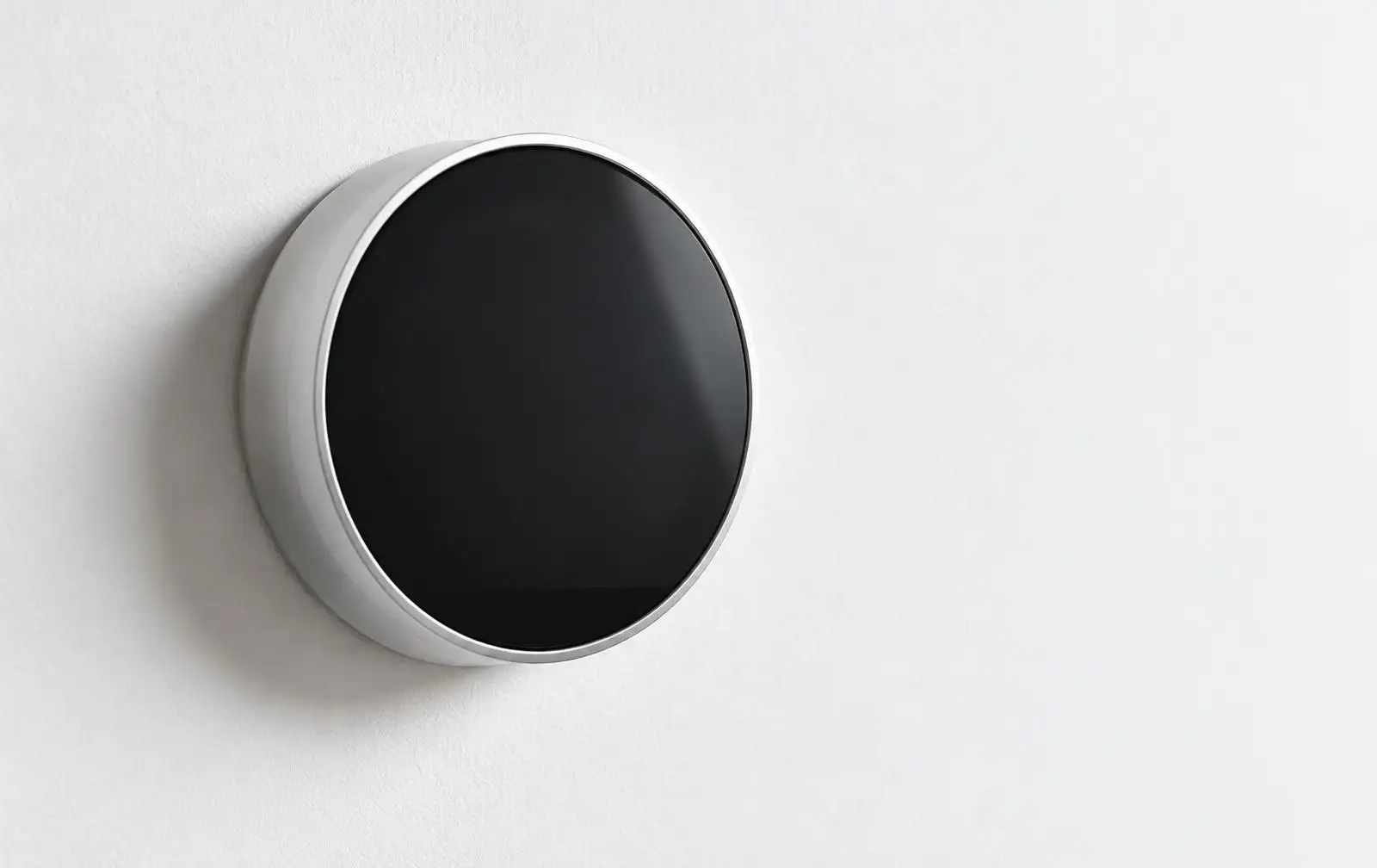 Round wall-mounted digital thermostat on a white wall